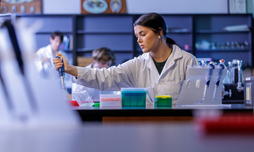 A student in a lab coat uses lab equipment