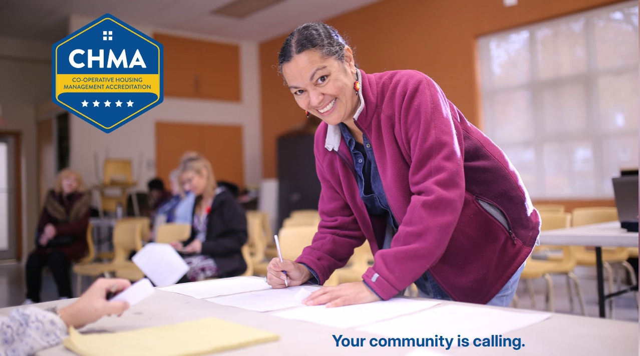 Community meeting setting with a person completing paperwork at a table in the foreground. The CHMA (Co-operative Housing Management Accreditation) logo is displayed in the upper left, with other attendees seated in the background. The image includes the slogan: “Your community is calling.”