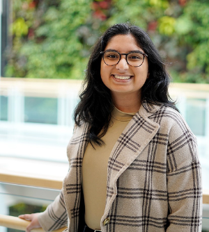 A student posing for a picture, leaning on a railing