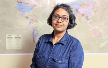 Madhuparna Gupta standing with a backdrop of a world map